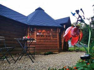 a log cabin with a table and a red flower at La cabane du Nuton Ardennais in Tournes +5 photos