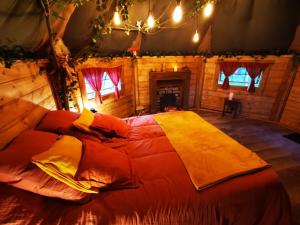 ein Schlafzimmer mit einem großen Bett in einem Blockhaus in der Unterkunft La cabane du Nuton Ardennais in Tournes