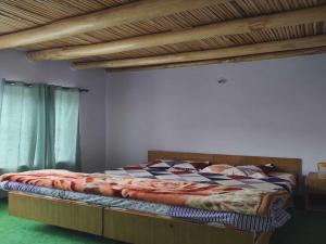 1 dormitorio con 1 cama con marco de madera en POP HOME 81129A Skayil Guest House en Nubra