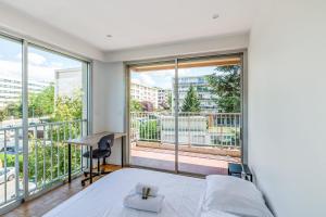 1 dormitorio con 1 cama, escritorio y ventanas en T4 with balcony in Lyon - Welkeys, en Lyon