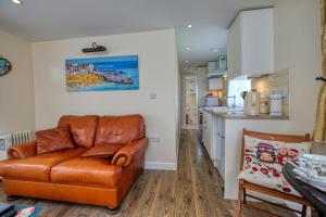 a living room with a brown leather couch and a kitchen at Two Hoots Chalet in Mundesley