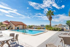 una piscina con mesas, sillas y una palmera en Sunset Harbor Palms 1-204, en Navarre