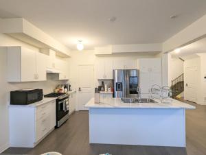 a large kitchen with white cabinets and a large island at PARADISE VILLa in Bowmanville