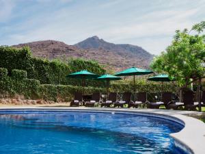 una piscina con sillas y sombrillas en Memora Chapala en Chapala