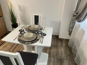 una mesa de comedor blanca con platos y vasos. en luxury central studio, en Hunedoara