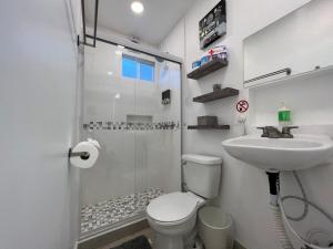 een badkamer met een toilet, een wastafel en een douche bij Las Mariposas Mini Suites in Rosarito