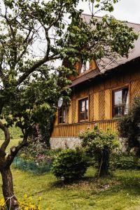 a wooden house with a tree in front of it at Wypoczynek u Agnieszki in Ochotnica Górna