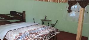 a bedroom with a bed and a table and a window at Cozy Huts in Nyandarua 