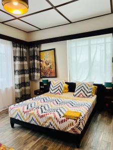 a bedroom with a bed with colorful sheets and pillows at La Villa Saint Jean in Cotonou