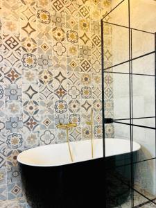 a bathroom with a tub and a tile wall at La Villa Saint Jean in Cotonou