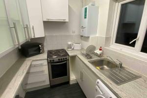 a kitchen with a sink and a stove top oven at Snug Kingsize bedroom flat in London in London