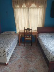 um quarto com 2 camas, uma mesa e uma cadeira em C.C. Habitaciones em Puerto Baquerizo Moreno