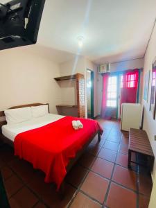 a bedroom with a bed with a red blanket at Pousada das Tartarugas in Rio das Ostras