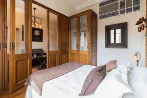 um quarto com uma cama branca e armários de madeira em The Wall Montevideo [001] Live in The Old Town em Montevidéu