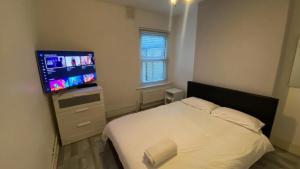 a bedroom with a bed and a flat screen tv at double and single bedrooms in London flat in London