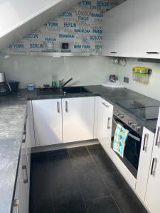 een keuken met witte kasten en een wastafel bij Moderne Ferienwohnung Neckarschleife mit Klimaanlage in Kirchheim am Neckar