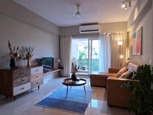 a living room with a couch and a table at Ripples:Pool facing/RiverView/7 mins to Coco Beach in Nerul