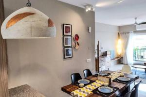 a dining room table with chairs and a large pendant light at Ripples:Pool facing/RiverView/7 mins to Coco Beach in Nerul