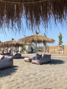 a group of pillows under a straw umbrella on the beach at Beachside Apartments Smajlaj in Velipojë