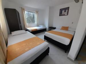 a hotel room with two beds and a window at Hotel Recuerdos del Estadio in Medellín