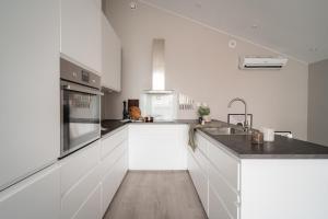 a white kitchen with white cabinets and a sink at Arctic Homes - Unique Town House in Tromsø