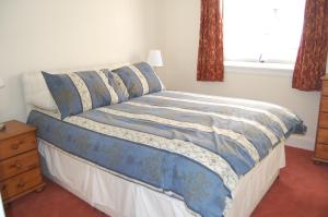 1 dormitorio con cama con sábanas azules y ventana en Anne House, Royal Mile, en Edimburgo