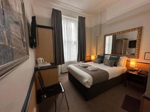 - une chambre d'hôtel avec un lit et un miroir dans l'établissement Tudor Court Hotel, à Londres