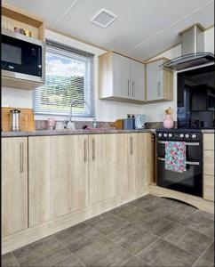 a kitchen with wooden cabinets and a stove top oven at Platinum Holiday Home by the Sea in Whitstable