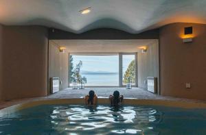 Dos personas sentadas en una piscina con vistas al océano en La Cascada Casa Patagónica by DON en San Carlos de Bariloche