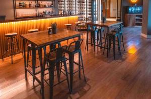 um bar com mesas de madeira e bancos de bar em La Cascada Casa Patagónica by DON em San Carlos de Bariloche