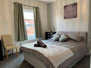 沃灵顿Spacious 2-Bedroom House In Stockton Heath With Free WiFi By Amazing Spaces Relocations Ltd的一间卧室配有一张带椅子的床和一扇窗户