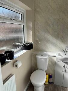 a bathroom with a toilet and a sink and a window at Spacious 2-Bedroom House In Stockton Heath With Free WiFi By Amazing Spaces Relocations Ltd in Warrington