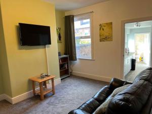 a living room with a couch and a flat screen tv at Spacious 2-Bedroom House In Stockton Heath With Free WiFi By Amazing Spaces Relocations Ltd in Warrington