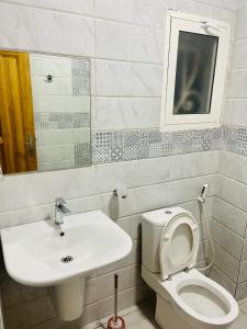 a bathroom with a sink and a toilet and a mirror at Johen Residence in Douala