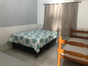a small bedroom with a bed with a flowered sheet at CASA TEMPORADA PRADO-BA in Prado