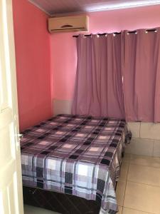 a small bedroom with a bed with pink walls at CASA TEMPORADA PRADO-BA in Prado