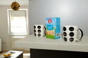 a counter with two coffee cups and a box of cereal at Apartman Skver in Tuzla