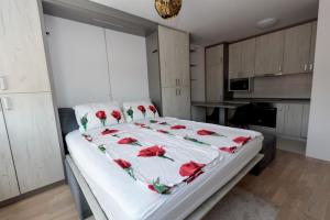 a bedroom with a bed with red roses on it at Apartman Skver in Tuzla