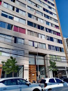 een hoog gebouw met auto's geparkeerd voor het bij Lindo Departamento Amoblado (Santiago) in Santiago