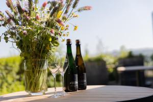 twee flessen wijn en een vaas met bloemen op een tafel bij Domein Holset BruisendWijnHuis in Lemiers