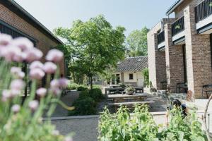 un jardin avec des tables et des fleurs devant deux bâtiments dans l'établissement Domein Holset BruisendWijnHuis, à Lemiers
