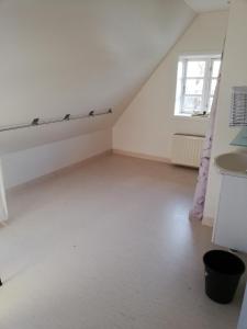 an attic room with white walls and a window at Skovhusets B&B i Gislev in Gislev