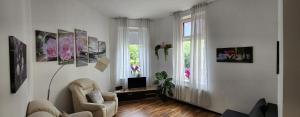 ein weißes Wohnzimmer mit einem Stuhl und einem TV in der Unterkunft ELENA flat Orchidee Duisburg Zentrum in Duisburg