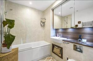 倫敦的住宿－Ontario Point Flat only double bedroom，带浴缸、水槽和镜子的浴室