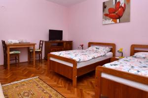 a room with two beds and a desk and a television at Štefanija Apartmani in Nedelišće