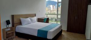 a bedroom with a bed and a large window at Hotel Royal Cid Bogota in Bogotá