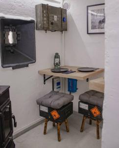 a room with a table and two stools and a tv at Vojenský bunker in Bratislava +16 photos