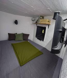 a small room with a green bed and a tv at Vojenský bunker in Bratislava