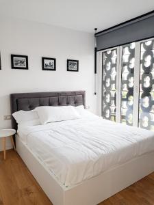 Cama blanca en habitación con ventana en Tirana Central Apartments - Premium en Tirana