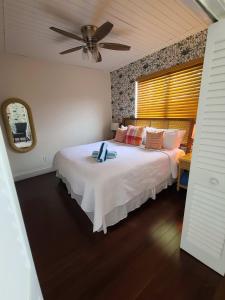 a bedroom with a large white bed with a fan at Duval Street Suite w parking and heated pool in Key West